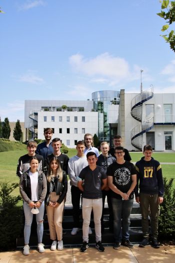 Die 12 neuen Azubis stehen in drei Reihen vor dem Gebäude des Leitplanken Herstellers MEISER Straßenausstattung GmbH.